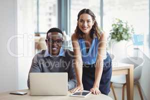 Portrait of smiling executives using laptop