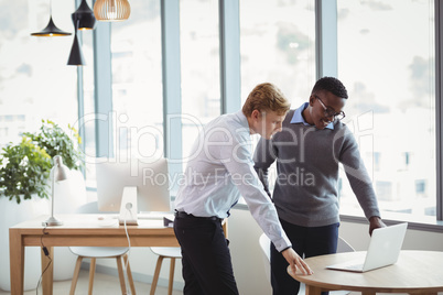 Attentive executives discussing over laptop