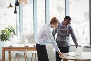 Attentive executives discussing over laptop