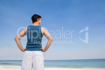 Man standing on beach with hand on hips