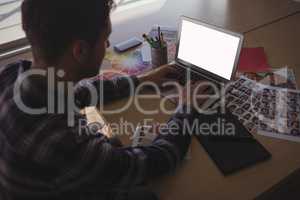 Male photo editor using laptop on desk in office