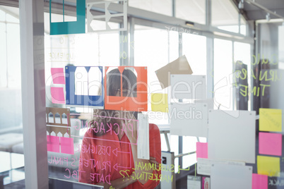 Businesswoman seen through adhesive notes on glass
