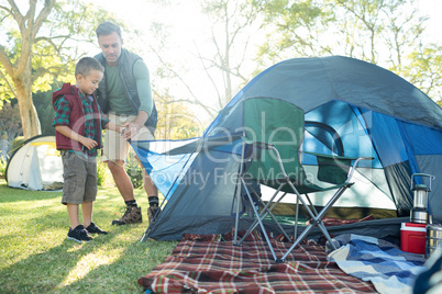 Father and son setting up the tent at campsite