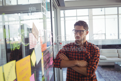 Thoughtful businessman looking at adhesive notes in office