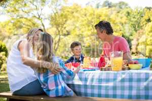 Happy family interacting with each other while having meal in park