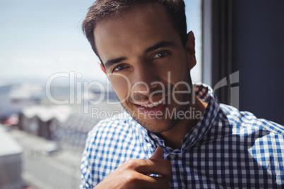 Portrait of young businessman by window in office