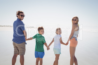 Portrait of family holding hands while standing on shore
