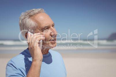 Senior man talking on mobile phone at beach