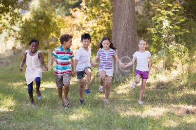 Friends holding hands while running at campsite