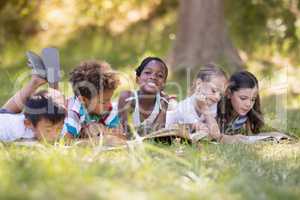 Friends reading book while lying on grassy field