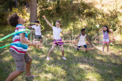 Cheerful friends playing with hula hoops at campsite