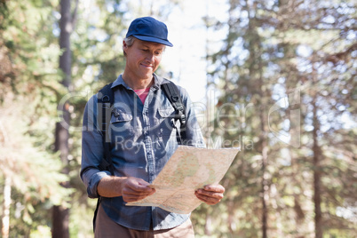 Happy hiker reading map in forest