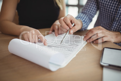 Mid section executives discussing over paper at desk