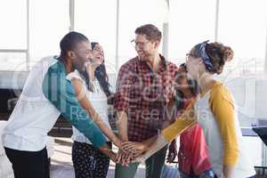 Happy friends stacking hands seen through glass