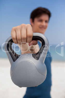 Man holding kettlebell at beach
