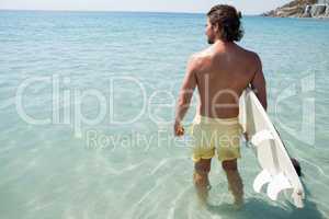 Surfer with surfboard looking at sea