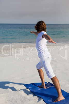 Man performing yoga at beach