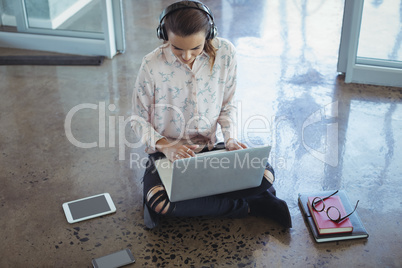 Entrepreneur wearing headphones while working on laptop