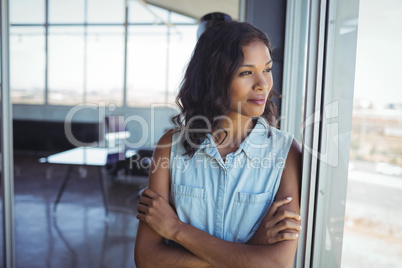 Thoughtful young businesswoman looking through window