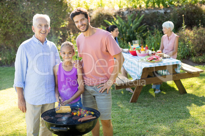 Girl, father and grandfather preparing barbecue in the park