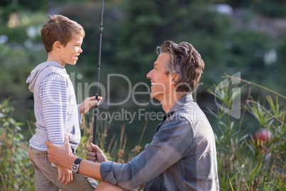 Smiling father and son holding fishing rod