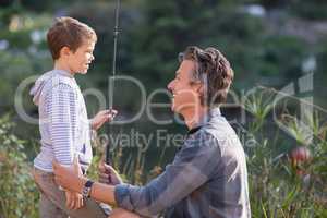 Smiling father and son holding fishing rod