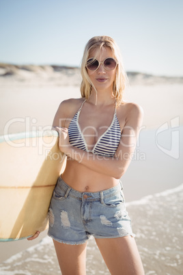 Portrait of young woman holding surfboard at beach