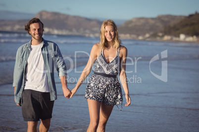 Portrait of happy couple holding hands on shore