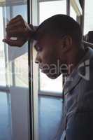 Close up of tired businessman leaning on glass