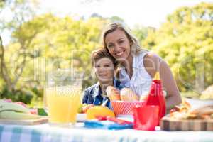 Portrait of happy mother and son having meal in park
