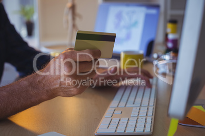 Cropped businessman shopping online with credit card at office