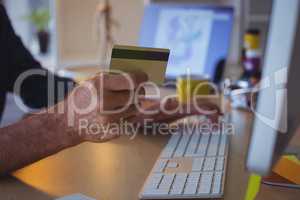 Cropped businessman shopping online with credit card at office