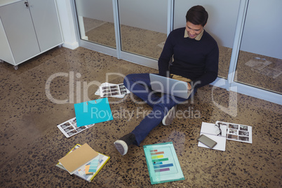Young businessman sitting on floor while working in creative office