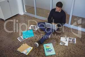 Young businessman sitting on floor while working in creative office