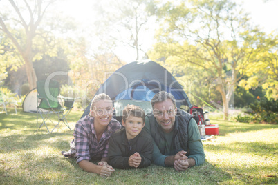 Father mother and son lying outside the tent at campsite