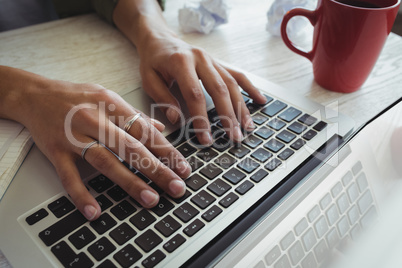 Hands of businesswoman using laptop on desk in office