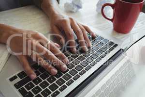 Hands of businesswoman using laptop on desk in office