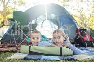 Smiling siblings lying outside the tent