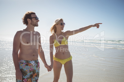 Woman gesturing while holding man hands at beach