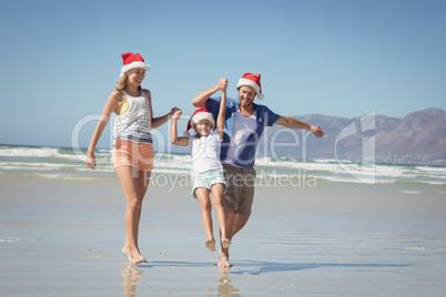 Happy family wearing Santa hat while enjoying at beach