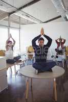 Young business people doing yoga at office