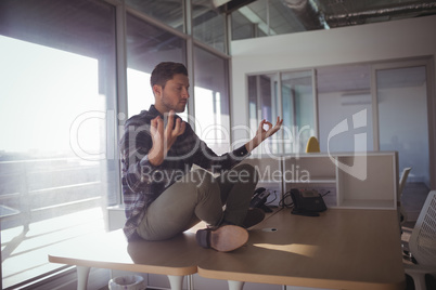Businessman meditating on table at office