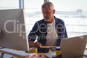 Serious businessman working on digitizer at office desk