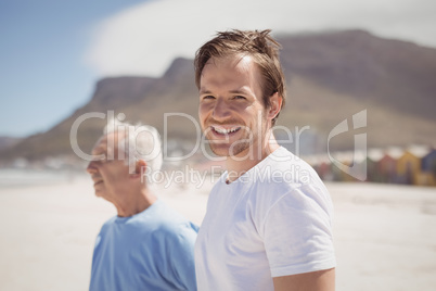 Portrait of young man with his father standing at beach