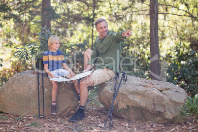 Father showing direction to son in forest