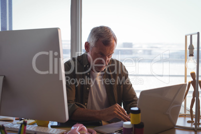 Serious businessman working on laptop at office desk