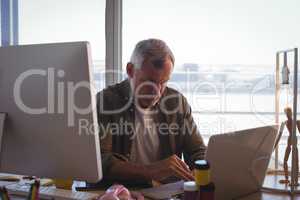 Serious businessman working on laptop at office desk