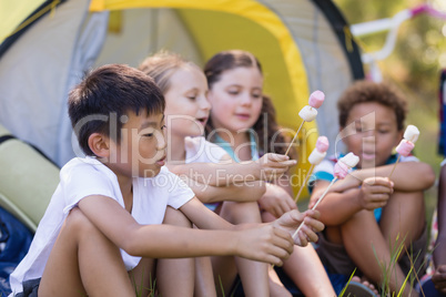 Friends holding candies by tent at campsite