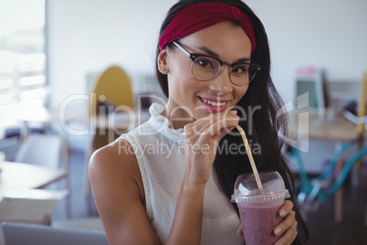 Portrait of smiling businesswoman holding drink at office