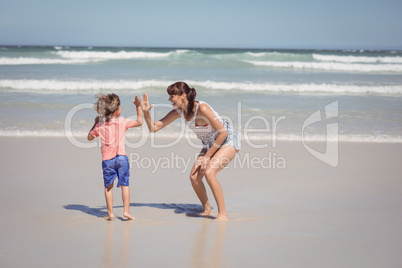 Boy giving high five to mother on shore